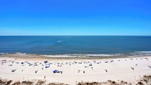A wide beach with clear skies and calm waters.