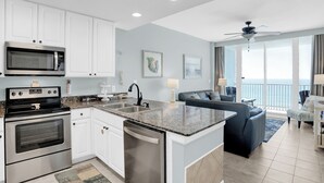 A modern kitchen with white cabinets, stainless steel appliances, and a granite countertop.