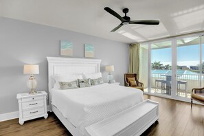 Un dormitorio espacioso con una cama grande, ventilador de techo y balcón con vistas.