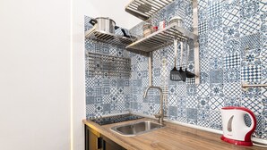 Una cocina con un lavamanos, una tetera y un salpicadero con azulejos azules y blancos.