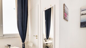 Un baño con lavamanos blanco, un espejo y una ventana con cortinas oscuras.