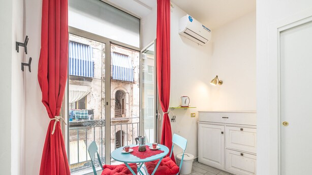 Una habitación compacta con balcón, una pequeña mesa con una taza y platillo, una silla y un armario.
