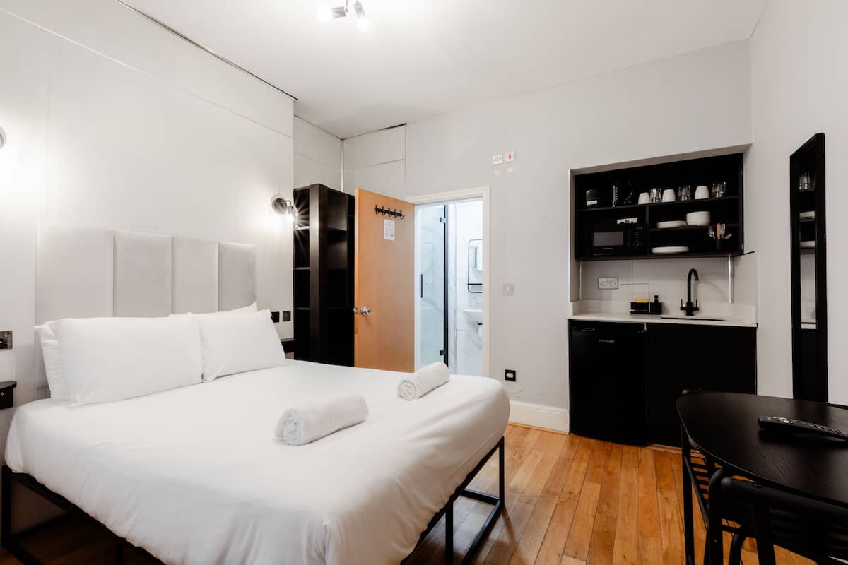 Una habitación de hotel moderna con una cama grande, un escritorio pequeño y una kitchenette.