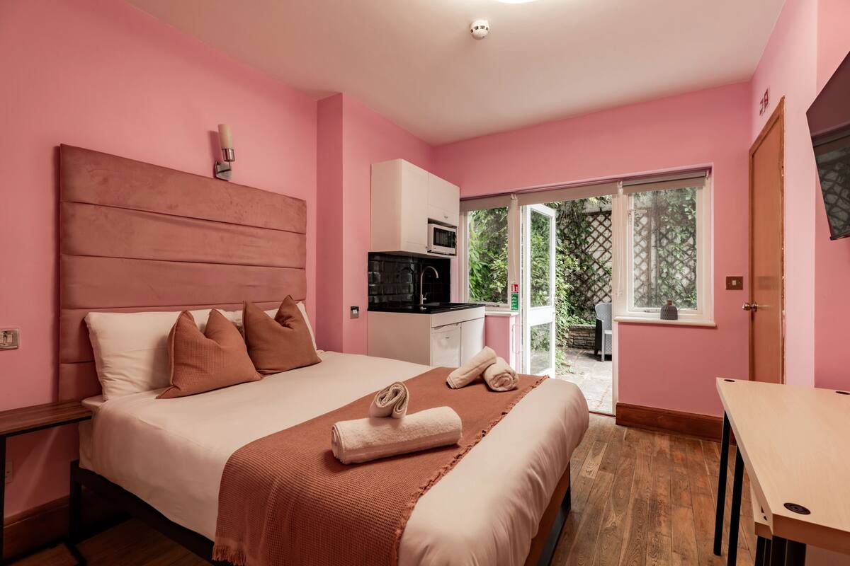 Un dormitorio con cama, mesita de noche, microondas y vistas al exterior.