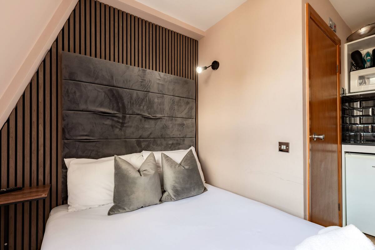 Un dormitorio con una cama grande, un cabecero de madera con listones, una mesita de noche y un armario empotrado.