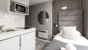 A modern bedroom with a bed, a bedside table, a mirror, and a wall-mounted radiator. - Britannia Hyde Park Hotel By PLI (London)