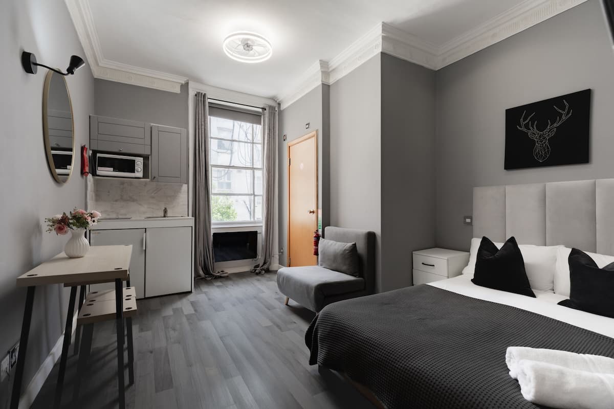 Una habitación de hotel moderna con cama, mesita de noche y una pequeña zona de estar.