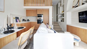 Eine moderne Küche mit Holzausstattung, einem Einbauofen und einem Essbereich mit weißem Tisch und Stühlen.