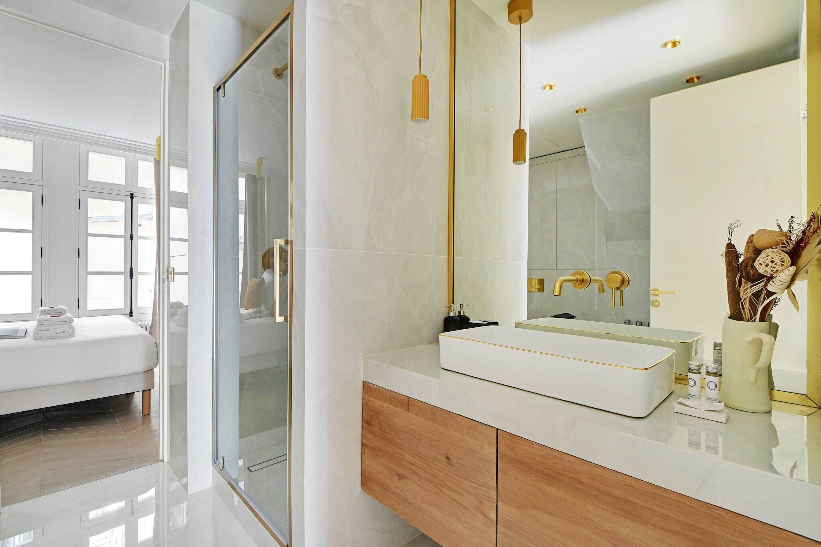 A modern bathroom with a glass shower door, a white sink, and a large mirror.