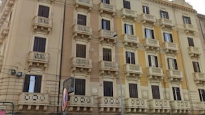 A multi-story building with balconies, a no parking sign, and cars parked in front. - Aurora Center City (Palermo)