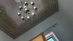 A room with a chandelier, a window with a view, and two framed pictures on the wall. - Aurora Center City (Palermo)