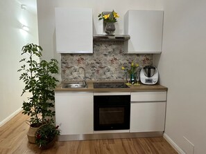 A compact kitchen with white cabinets, a stainless steel sink, a built-in oven, and a backsplash with a marbled pattern. - Aurora Center City (Palermo)