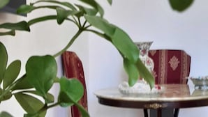 A dining area with a round table, red upholstered chairs, and a vase with white flowers. - Aurora Center City (Palermo)