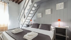 A modern bedroom with a large bed, a nightstand, a lamp, and a staircase. - Le Casine Firenze (Florence)