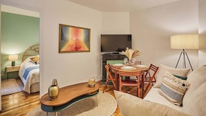 A living room with a TV, a dining table with chairs, a sofa, and a lamp. - Superb Apartment Le Marais/place des Vosges (Paris)