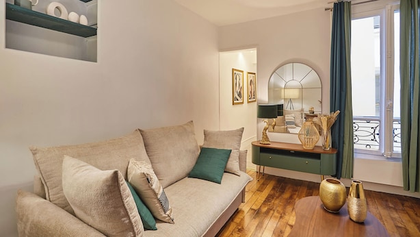 A living room with a beige sofa, a wooden coffee table, and a mirror above a console table. - Superb Apartment Le Marais/place des Vosges (Paris)