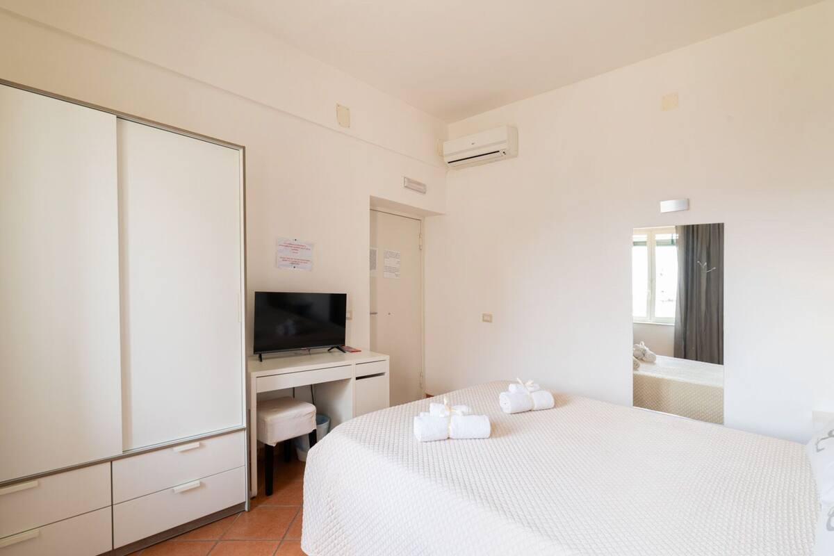 A hotel room with a bed, a TV, a desk, and a wardrobe.