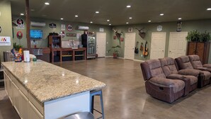 Amplia sala de estar con encimera de granito, barra y zona de estar con sillones reclinables.