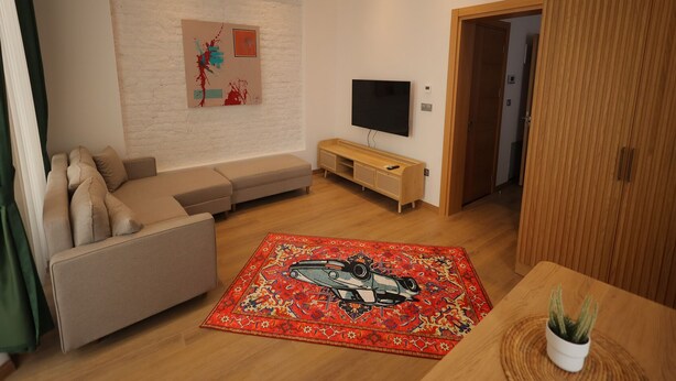 Uma sala de estar moderna com sofá, televisão de tela plana, armário de madeira e tapete vermelho estampado.