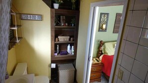 Un baño pequeño y funcional con inodoro, un estante con artículos de aseo y un espacio de almacenamiento.