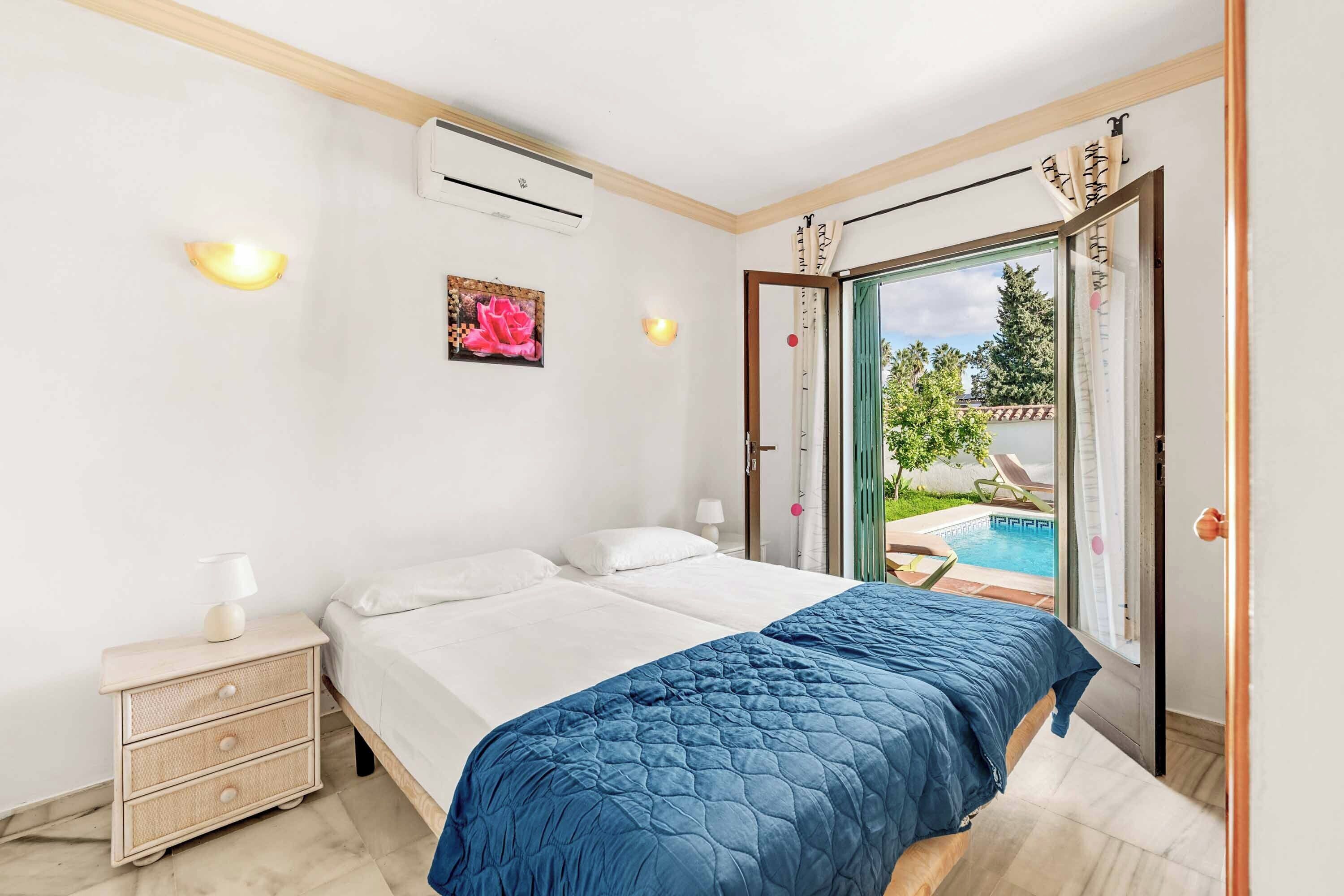 Una camera da letto con un letto, un comodino, un condizionatore e vista su una piscina.