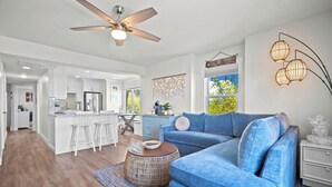 A modern living room with a blue sofa, a round wooden coffee table, and a ceiling fan. - Ocean View Condo, Golf Cart Included, Private Patio, Newly Redecorated - 607 Newhaven (Fripp Island)