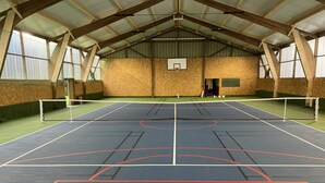 Ein Hallensportfeld mit Basketballkorb, Holzbalken und Netz.