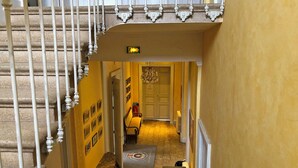 Ein schmaler Flur mit einer Treppe links, einer Bank und einem Heizkörper rechts.