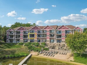 Un hotel de varios pisos con balcones, un jardín ajardinado y un estanque.