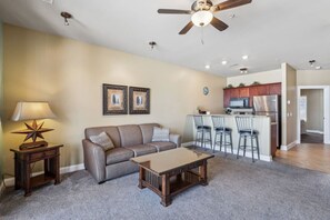 A living room with a sofa, a coffee table, a lamp, and a ceiling fan.