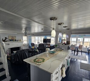 A spacious kitchen with a large island, white cabinetry, and a view of the outdoors through the windows.