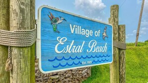 Un panneau indiquant l’entrée du village d’Estral Beach, avec une illustration d’oiseau et un motif représentant une vague.