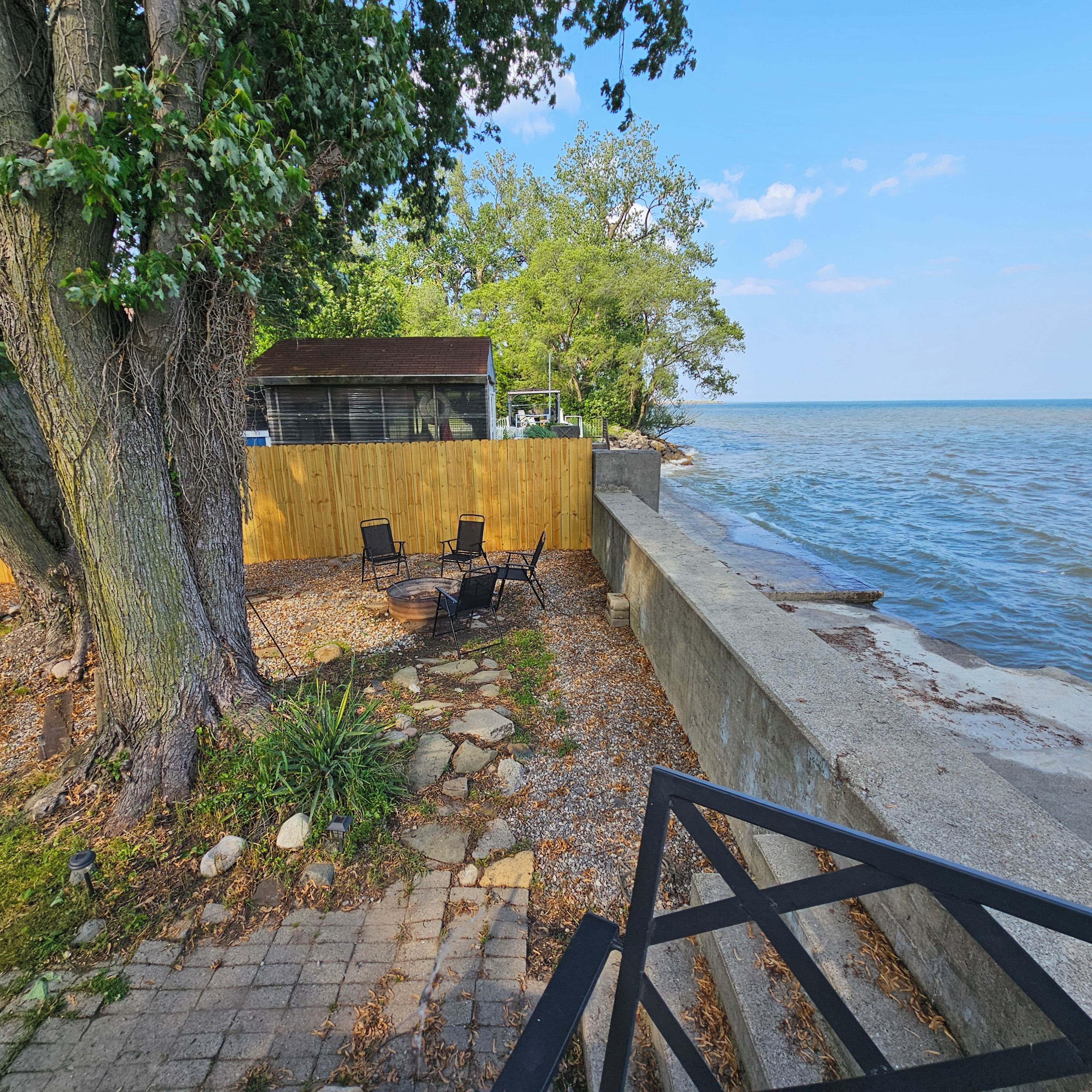 A waterfront property with a wooden deck, outdoor seating, and a view of the water.