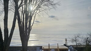 Un chemin de pierres mène à une terrasse en bois qui surplombe une étendue d’eau.