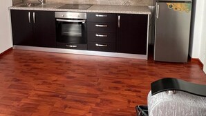 A compact kitchen with dark cabinets, a stainless steel refrigerator, and a built-in oven.