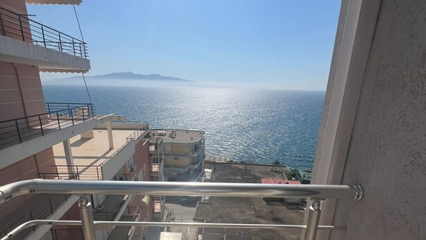 A balcony with a metal railing overlooking a coastal view.