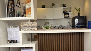 Une cuisine moderne avec des meubles blancs, un four à micro-ondes, un réfrigérateur et un mur recouvert de panneaux en bois.