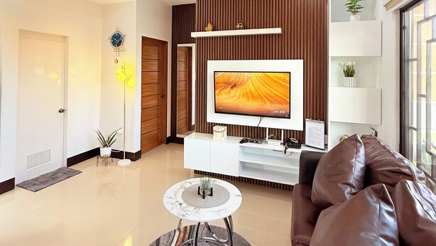 Ein modernes Wohnzimmer mit Flachbildfernseher, Ledersofa und Couchtisch.