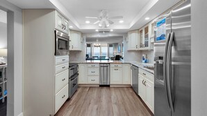 Une cuisine moderne avec des meubles blancs, des appareils en acier inoxydable et un îlot central.