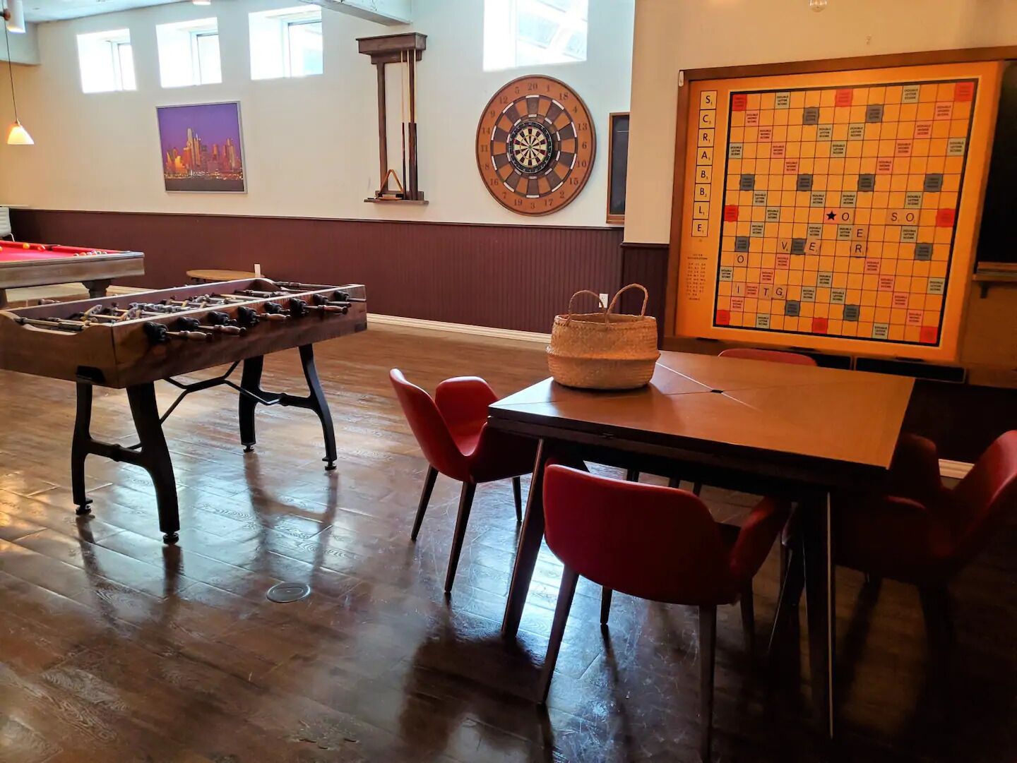 Una habitación con mesa de futbolín, dardos y juego de Scrabble.