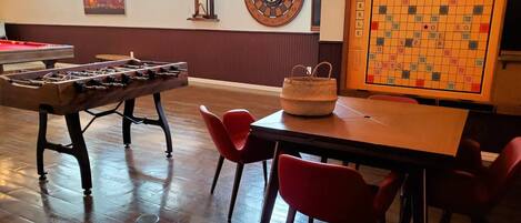 Una habitación con mesa de futbolín, dardos y juego de Scrabble.