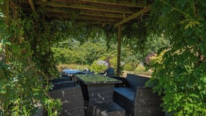 Een buitenterras met rieten meubilair en een pergola.