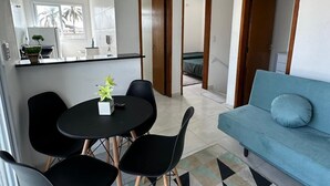 Una sala de estar moderna con un sofá azul, una mesa de comedor con sillas y una alfombra estampada con motivos geométricos.