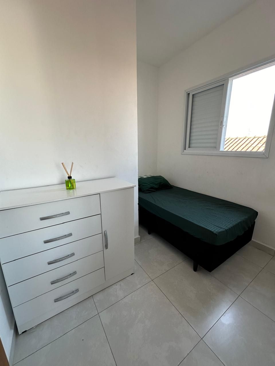 A small, clean room with a single bed, a white dresser with drawers, and a window with blinds.