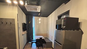 A compact kitchen with a microwave, refrigerator, and dining area. - Das Schlafwerk Köln-Messe (Cologne)