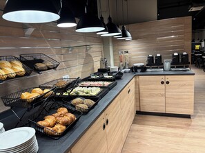 Montaje de bufé con diferentes alimentos y máquinas de café.