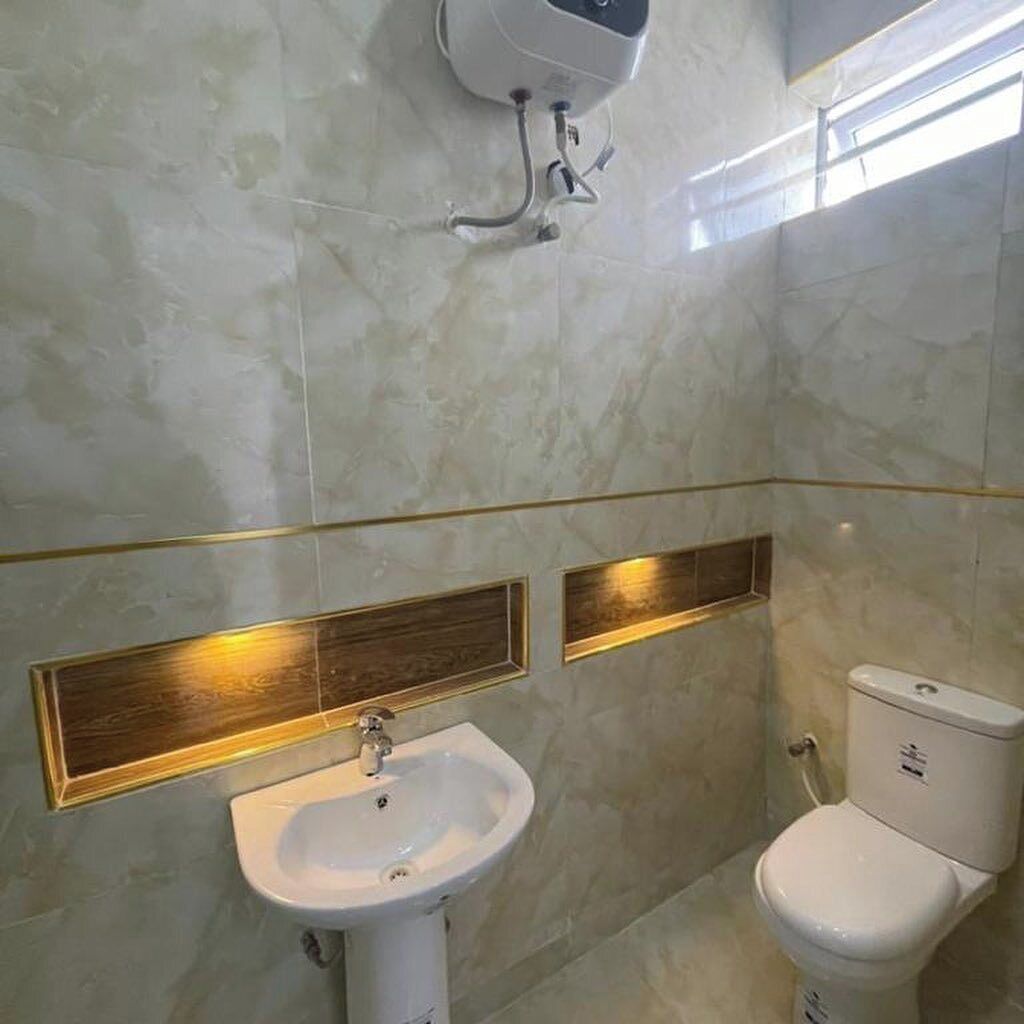 A bathroom with a white sink, a toilet, and a wall-mounted air purifier.