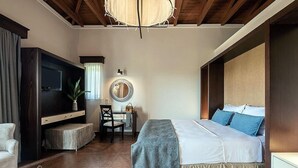 Un dormitorio con cama, escritorio, silla, televisor y ventana.