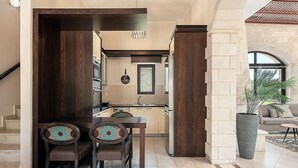 Una cocina moderna con armarios de madera oscura, un comedor con dos sillas y una planta grande en maceta.