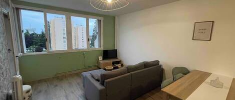A modern living room with a sofa, a TV, and a dining table.